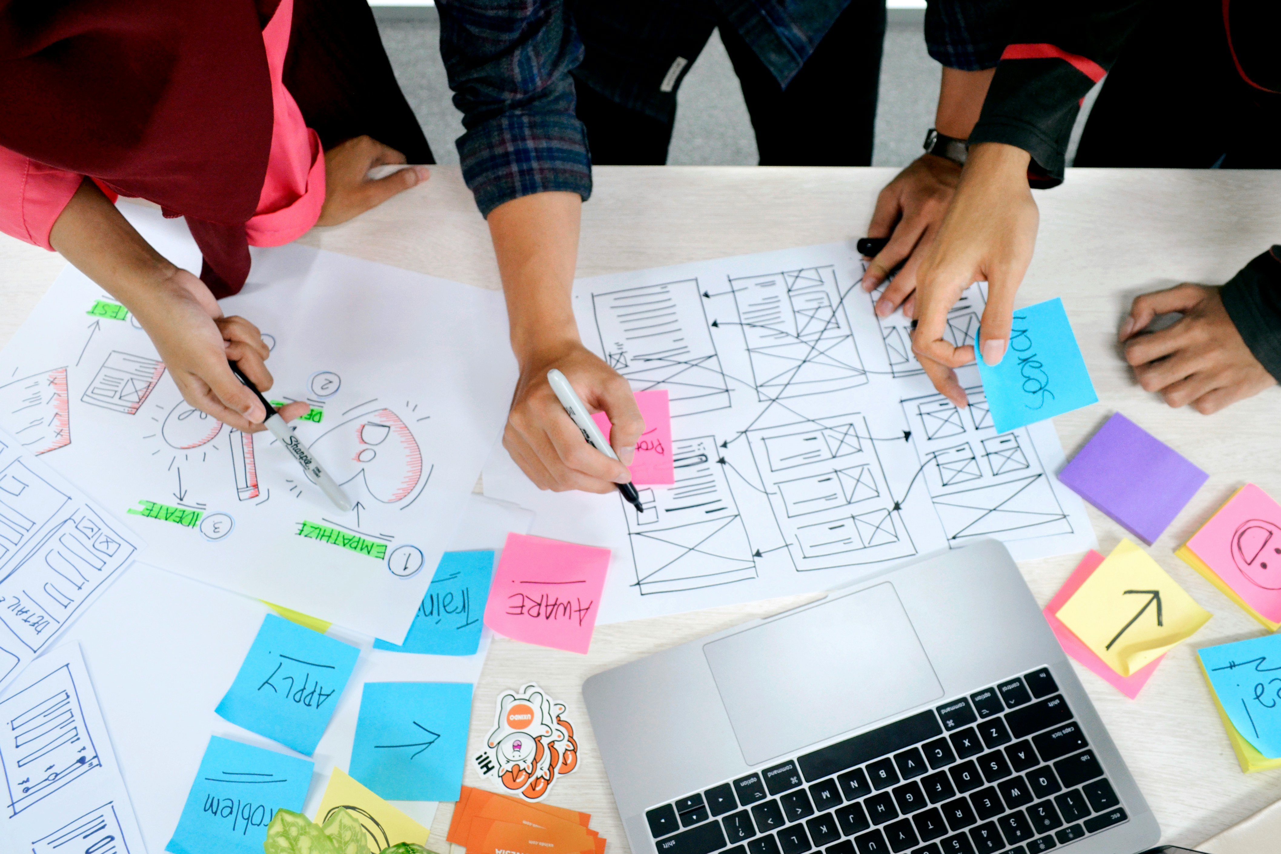 People planning a project with paper, laptop and sticky notes